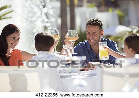 Family with two children raising toast at table outdoors View Large Photo Image Stock Photography - Family with two children raising toast at table outdoors. Fotosearch