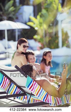 Family with two children relaxing by resort swimming pool View Large Photo Image Picture - Family with two children relaxing by resort swimming pool. Fotosearch