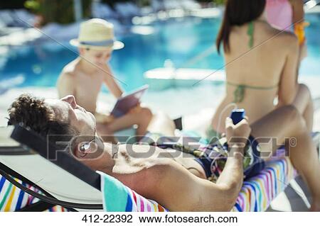 Family with two children sunbathing by resort swimming pool View Large Photo Image Stock Image - Family with two children sunbathing by resort swimming pool. Fotosearch