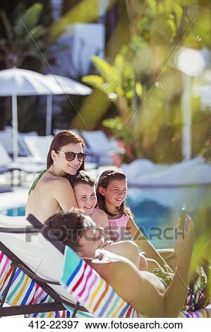 Stock Photo - Family with two children sunbathing by resort swimming pool. Fotosearch