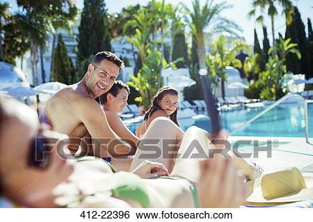 Family with two children sunbathing by resort swimming pool View Large Photo Image Stock Photograph - Family with two children sunbathing by resort swimming pool. Fotosearch