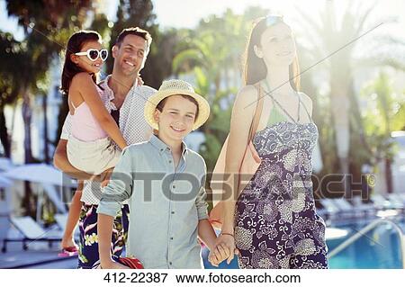 Stock Photo - Family with two children walking by resort swimming pool. Fotosearch
