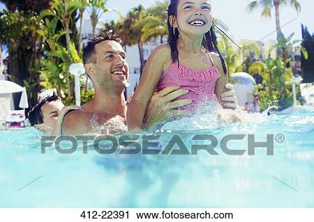 Stock Image - Father with daughter and son playing in swimming pool. Fotosearch