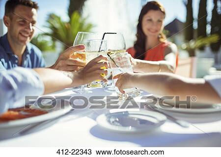 Stock Image - Friends raising toast at table outdoors. Fotosearch