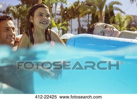 Girl swimming with her parents in swimming pool View Large Photo Image Stock Photography - Girl swimming with her parents in swimming pool. Fotosearch