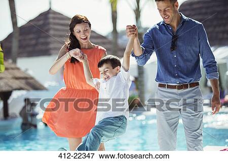 Stock Photo - Little boy having fun with his parents by swimming pool. Fotosearch