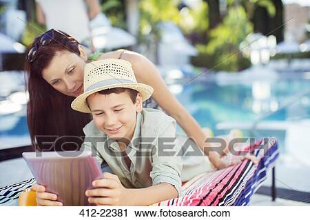 Mother and son using tablet pc by swimming pool View Large Photo Image Stock Image - Mother and son using tablet pc by swimming pool. Fotosearch