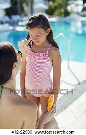 Mother applying suntan lotion on daughter's face by swimming pool View Large Photo Image Stock Photograph - Mother applying suntan lotion on daughter's face by swimming pool. Fotosearch