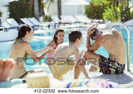 Stock Image - Playful family with two children on poolside. Fotosearch