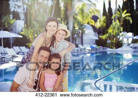 Stock Image - Portrait of happy family with son and daughter by swimming pool. Fotosearch