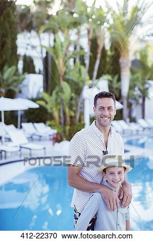 Portrait of smiling father and son standing by resort swimming pool View Large Photo Image Stock Image - Portrait of smiling father and son standing by resort swimming pool. Fotosearch