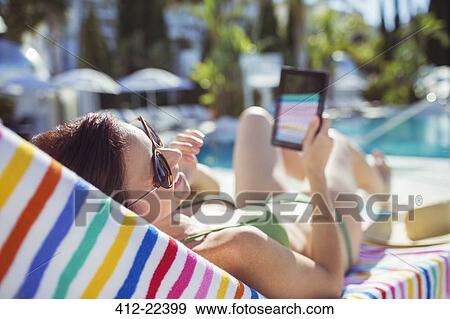 Smiling woman with digital tablet sunbathing by swimming pool View Large Photo Image Stock Photo - Smiling woman with digital tablet sunbathing by swimming pool. Fotosearch