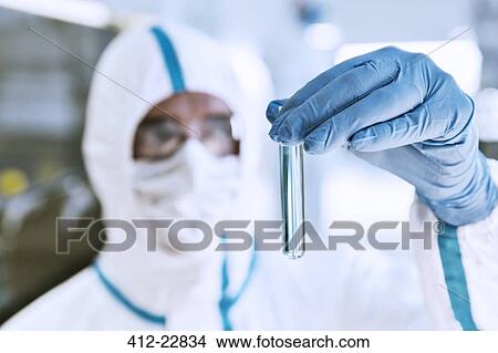 Close up of scientist in clean suit examining sample in test tube View Large Photo Image Picture - Close up of scientist in clean suit examining sample in test tube. Fotosearch