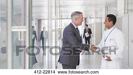 Picture - Scientist and businessman shaking hands in hallway. Fotosearch
