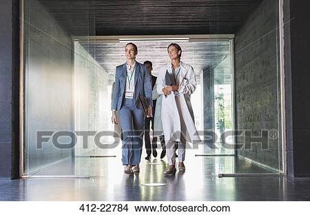 Scientist and businesswoman walking in hallway View Large Photo Image Picture - Scientist and businesswoman walking in hallway. Fotosearch