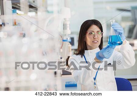 Stock Image - Scientist examining sample in beaker in laboratory. Fotosearch