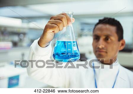 Stock Photograph - Scientist examining sample in beaker in laboratory. Fotosearch