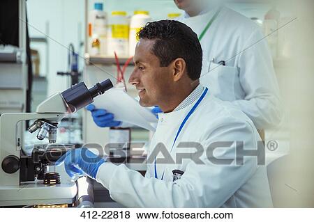 Scientist examining sample under microscope in laboratory View Large Photo Image Stock Photo - Scientist examining sample under microscope in laboratory. Fotosearch