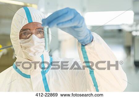 Stock Photo - Scientist in clean suit examining sample in test tube in laboratory. Fotosearch