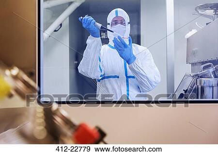 Stock Photo - Scientist in clean suit pipetting sample into Petri dish in laboratory. Fotosearch
