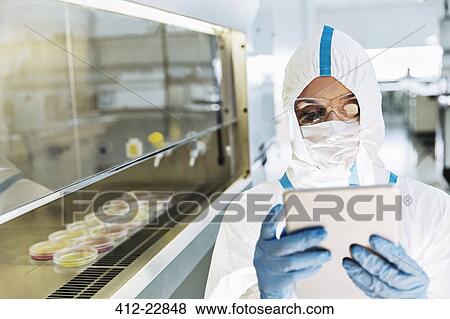 Scientist in clean suit using digital tablet in laboratory View Large Photo Image Stock Photo - Scientist in clean suit using digital tablet in laboratory. Fotosearch