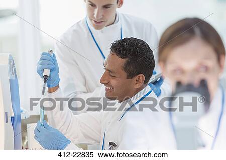 Stock Photography - Scientist pipetting sample into test tube in laboratory. Fotosearch