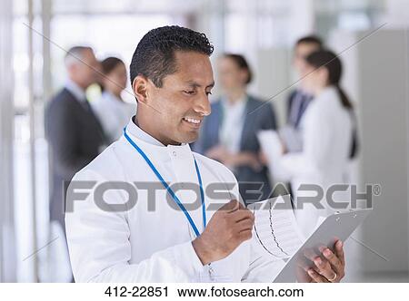Stock Image - Scientist reading clipboard in hallway. Fotosearch