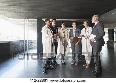Stock Image - Scientists and business people talking in lobby. Fotosearch