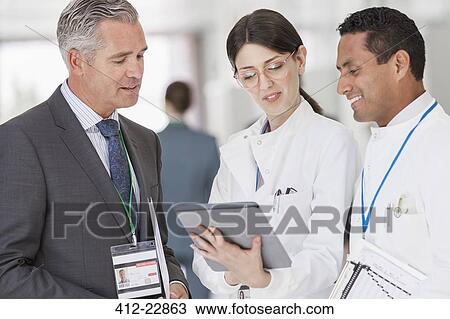 Stock Image - Scientists and businessman reading digital tablet. Fotosearch