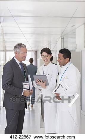 Scientists and businessman using digital tablet in hallway View Large Photo Image Stock Photo - Scientists and businessman using digital tablet in hallway. Fotosearch