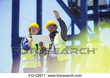 Businessman and worker talking near cargo crane View Large Photo Image Stock Image - Businessman and worker talking near cargo crane. Fotosearch