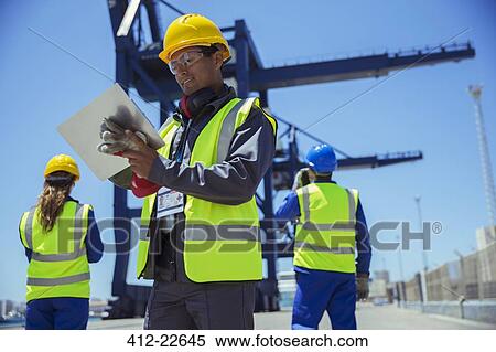 Businessman holding clipboard near cargo crane View Large Photo Image Stock Photography - Businessman holding clipboard near cargo crane. Fotosearch