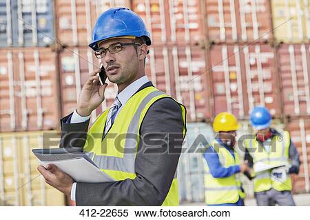 Businessman talking on cell phone near cargo containers View Large Photo Image Stock Photography - Businessman talking on cell phone near cargo containers. Fotosearch