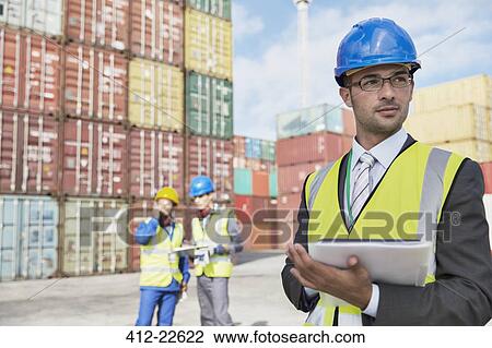 Businessman using digital tablet near cargo containers View Large Photo Image Stock Image - Businessman using digital tablet near cargo containers. Fotosearch