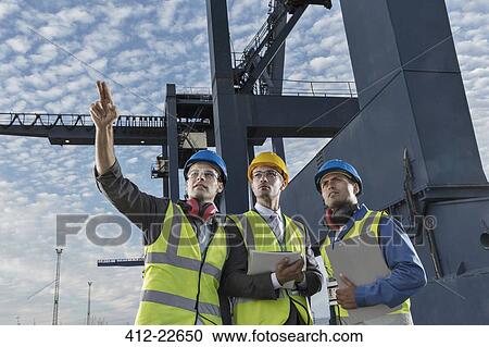 Businessmen and worker talking near cargo crane View Large Photo Image Stock Image - Businessmen and worker talking near cargo crane. Fotosearch