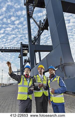 Businessmen and worker talking near cargo crane View Large Photo Image Stock Image - Businessmen and worker talking near cargo crane. Fotosearch