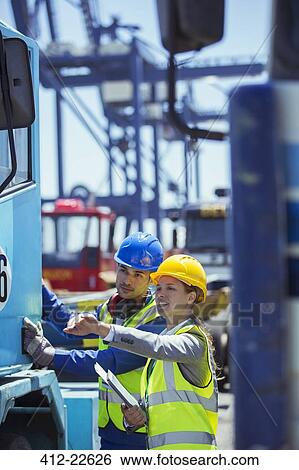 Businesswoman and worker examining truck near cargo crane View Large Photo Image Stock Photograph - Businesswoman and worker examining truck near cargo crane. Fotosearch