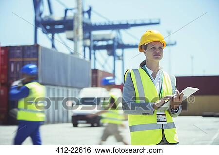 Stock Photograph - Businesswoman using digital tablet near cargo containers. Fotosearch