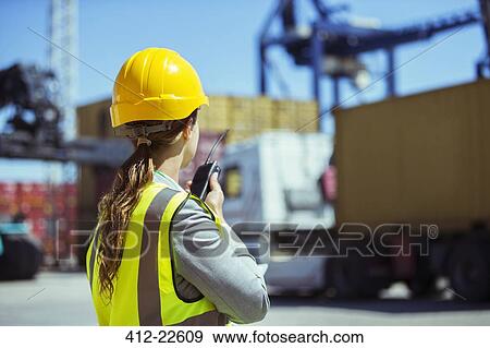 Businesswoman using walkie-talkie near cargo containers View Large Photo Image Stock Photo - Businesswoman using walkie-talkie near cargo containers. Fotosearch