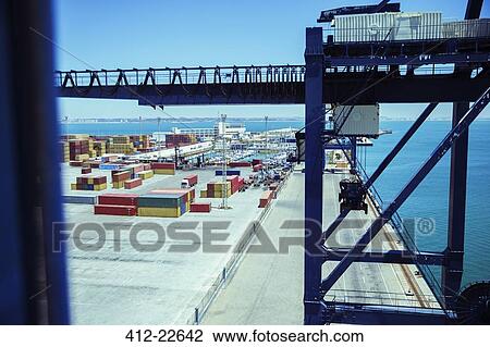 Stock Image - Crane and cargo containers at waterfront. Fotosearch