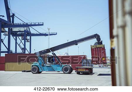 Stock Image - Crane lifting cargo container onto truck. Fotosearch