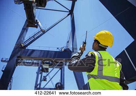 Low angle view of businessman using walkie-talkie under cargo crane View Large Photo Image Stock Image - Low angle view of businessman using walkie-talkie under cargo crane. Fotosearch