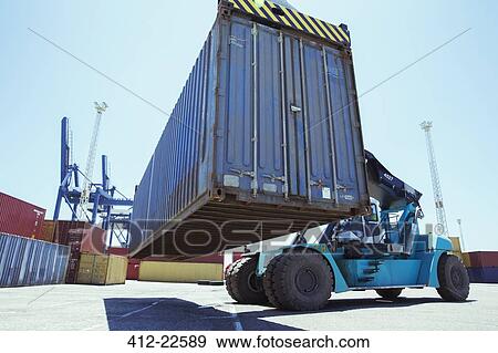Stock Photo - Low angle view of crane lifting cargo container. Fotosearch
