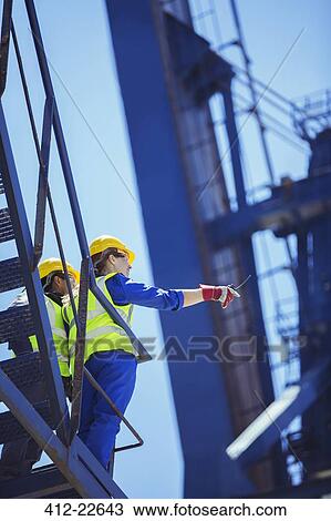 Low angle view of workers on cargo crane View Large Photo Image Stock Image - Low angle view of workers on cargo crane. Fotosearch
