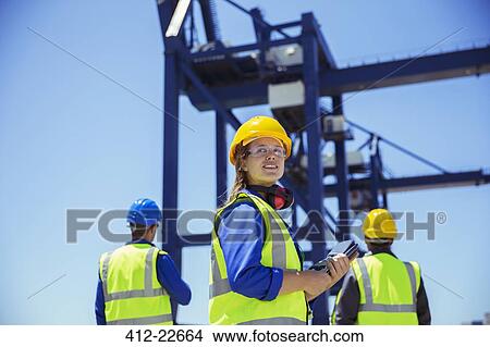Low angle view of workers standing under cargo crane View Large Photo Image Picture - Low angle view of workers standing under cargo crane. Fotosearch