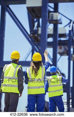 Stock Photograph - Worker and businessman examining cargo crane. Fotosearch