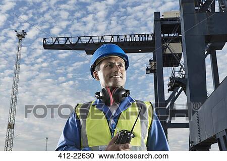 Worker smiling near cargo crane View Large Photo Image Stock Image - Worker smiling near cargo crane. Fotosearch