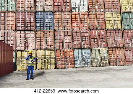 Worker standing near cargo containers View Large Photo Image Stock Photo - Worker standing near cargo containers. Fotosearch