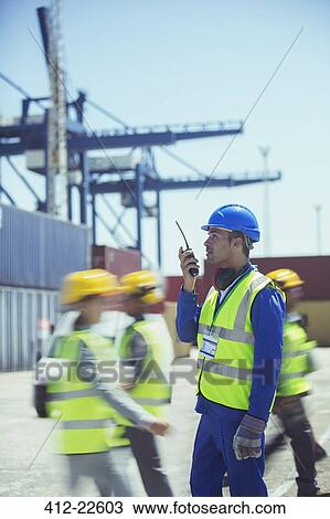 Worker using walkie-talkie near cargo containers View Large Photo Image Stock Image - Worker using walkie-talkie near cargo containers. Fotosearch