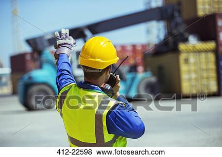 Worker using walkie-talkie near cargo containers View Large Photo Image Stock Photo - Worker using walkie-talkie near cargo containers. Fotosearch